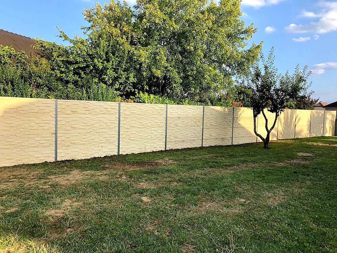 Mur de clôture en béton aspect pierre, ton sable, en limite de jardin